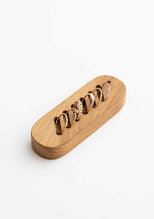 A wooden ring holder with a simple chevron style slot for holding rings, displayed against a white background.