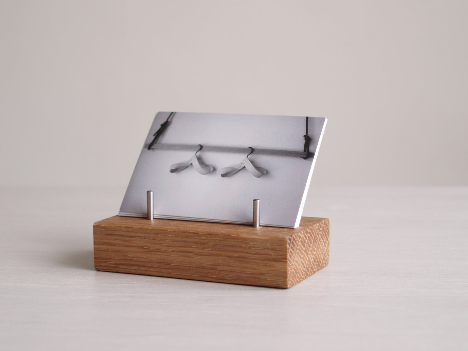 A small block of solid oak with four stainless steel pins, used for holding business cards.